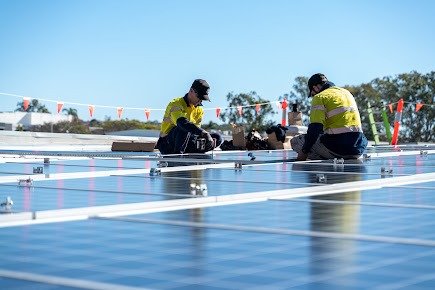 Instaladores trabajando en campo de paneles solares sobre cubierta industrial