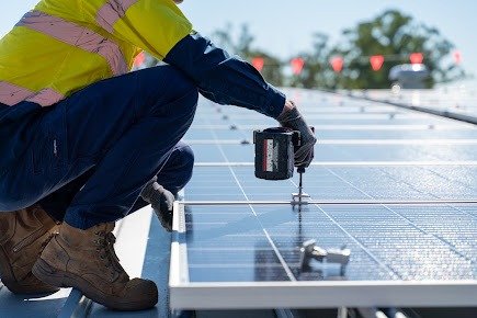 Técnico atornillando paneles solares sobre cubierta metálica