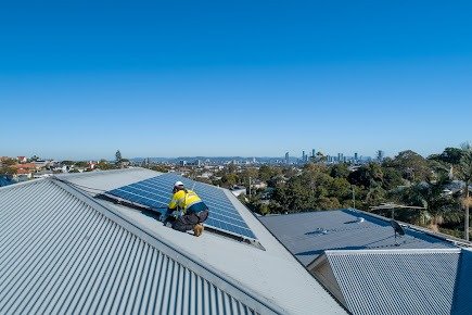 Instalador de placas solares trabajando en cubierta con vista al skyline